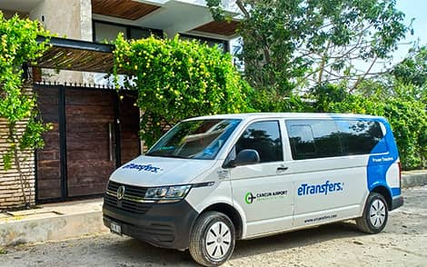 Photograph of a Cancun airport transportation passenger van with the etransfers logo parked in front of a hotel.